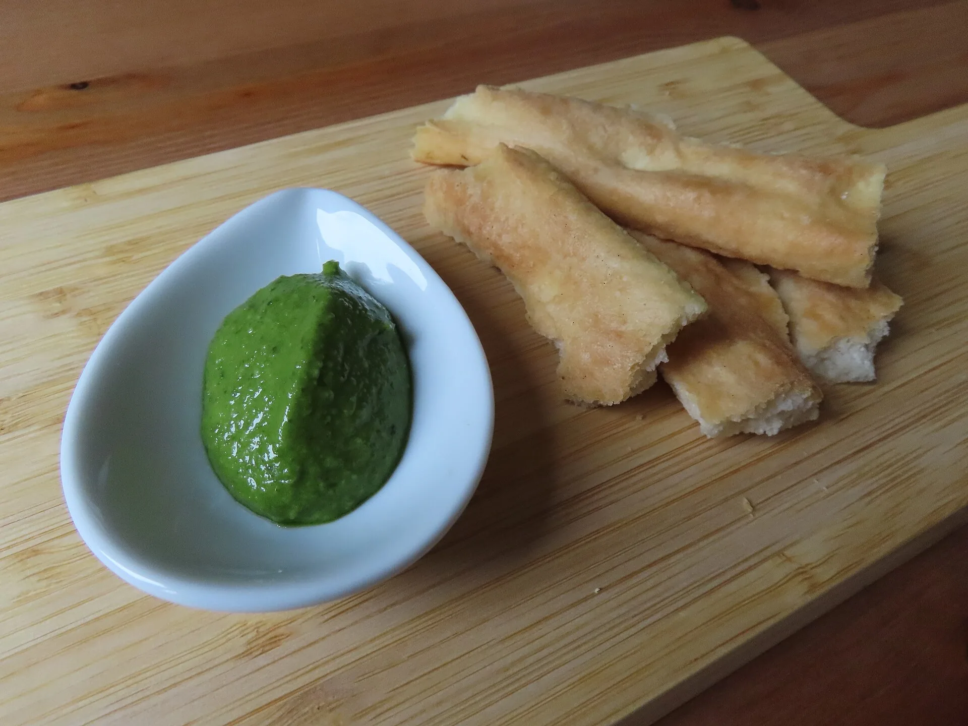 Pesto alla genovese servito con strisce di focaccia su un tagliere